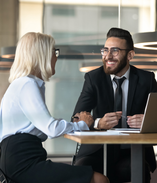 Man and woman smiling while working in an office on a laptop