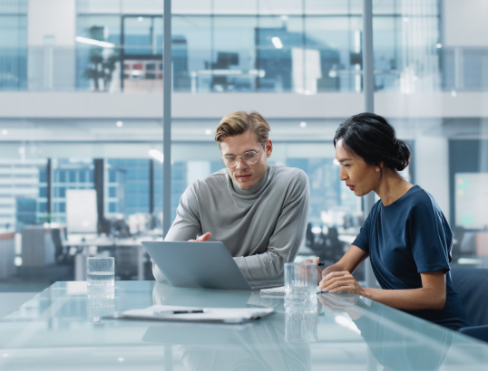 Man and woman working in an office looking at a laptop