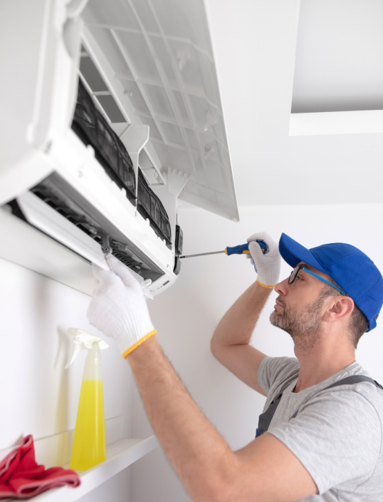 Man using a screwdriver on a wall mounted air conditioner