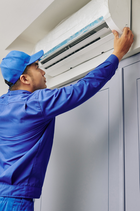 Man servicing a wall mounted air conditioning unit