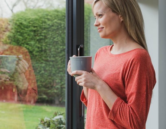 Woman with a mug looking out the window of her garden office