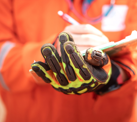 Hand in a protective glove holding a clipboard