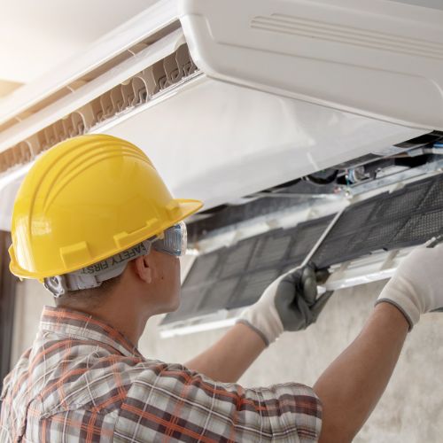 person with a hard hat installing an air con unit